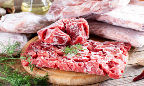 Raw steak laid out on a cutting board with thyme on top of it